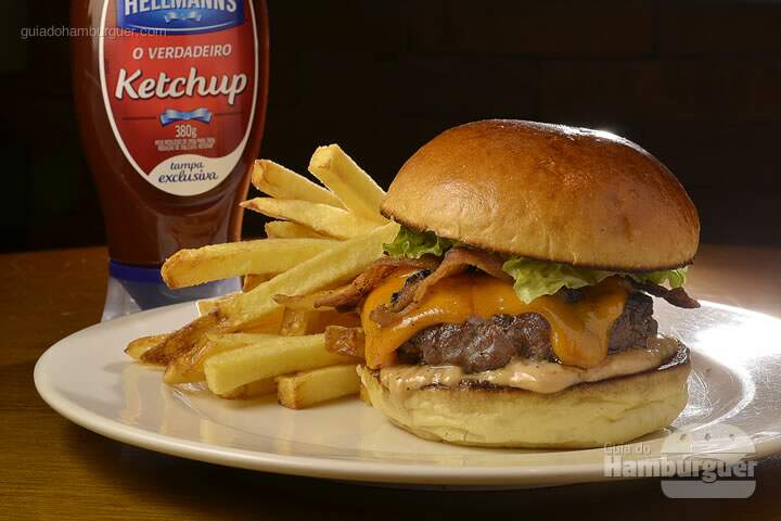 Triumph Bonneville Burger: Hambúrguer de blend de carnes (costela, shoulder e alcatra), cheddar, bacon, alface e molho especial Hellmann's da Chef, no pão de brioche. acompanha batata frita. - R$ 39 - SP Burger Fest