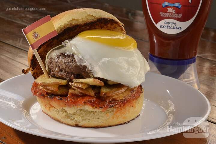 La Rambla Burger: Hambúrguer de 140g com cortes de carnes especiais do Chef, bacon canadense picado na ponta da faca misturado na carne, uma camada de finas batatas rústicas fritas, queijo mozzarella, molho especial com Ketchup Hellmann's e temperos espanhóis e ovo orgânico frito no pão artesanal de brioche. -  R$ 28  - SP Burger Fest