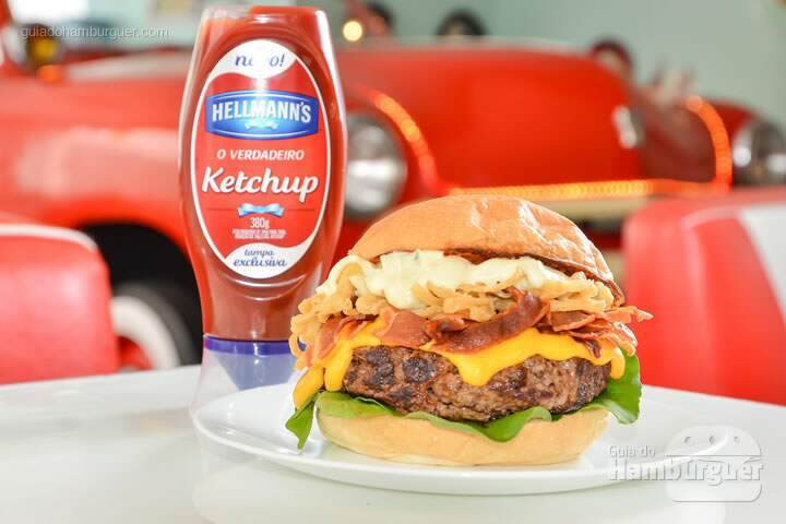 Sinatra Burger: Pão chapeado na manteiga, hambúrguer de picanha de 150g, creme de cheddar, rúcula, bacon, creme de queijo e onion rings. - R$ 33,90 - SP Burger Fest