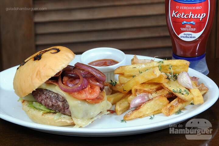 Rocky Burger Hambúrguer de costela com queijo emmental, bacon levemente curado, alface americana, tomate defumado e cebola roxa. Acompanhado de batatas rústicas com tomilho e alho, maionese de salsa e ketchup de goiabada.