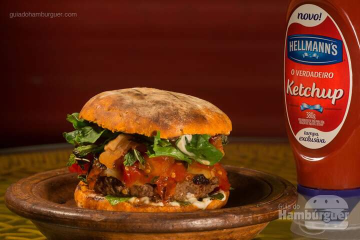 El Chivito Palomar (R$ 29,50): Suculento hambúrguer de cordeiro na brasa (200 g),  servido no pão caseiro de tomate, temperado com maionese de hortelã e coberto com   bacon, geleia de tomate e rúcula. - Burger Fest Vitória
