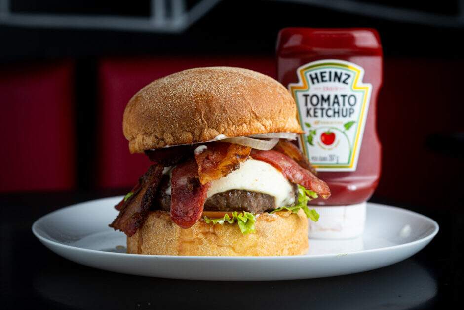 Hambúrguer de costela bovina com 200g, queijo canastra, fatias de calabresa, fatias de bacon caramelizado, cebola roxa em rodelas, alface, tomate, maionese defumada no pão de milho tostado com manteiga de garrafa acompanhado de batata frita.