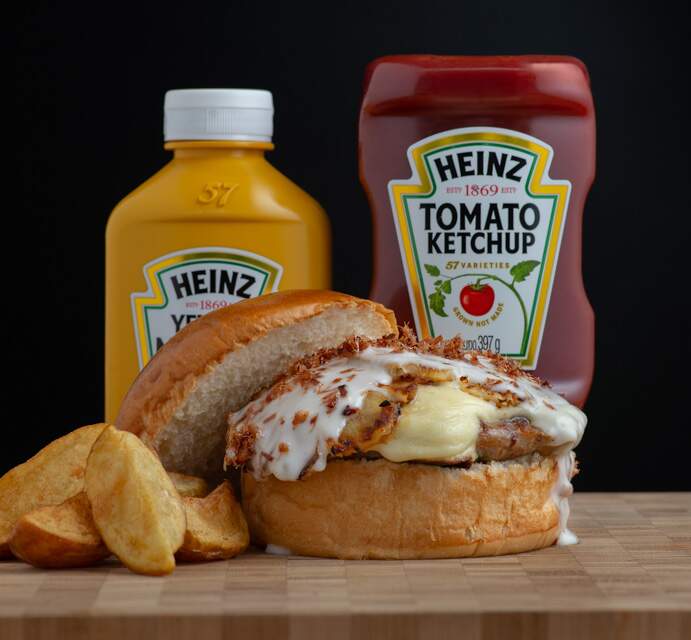 Hambúrguer feito com um blend de suíno e linguiça calabresa, queijo, carpaccio de abacaxi grelhado, maionese de leite temperada com crispy de bacon.
