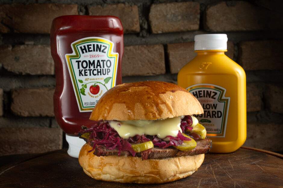 Peito bovino Hereford defumado no Pit, pão brioche, conserva de repolho roxo, picles e maionese de raiz forte.