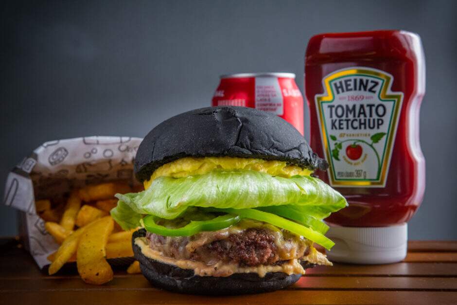 Inspirado pela cidade de Damasco e os cores da bandeira dos refugiados, JoJo's é feito com pão preto artesanal, 150g blend, homus, queijo mussarela, pimentão verde, alface, e maionese caseiro de damasco seco.