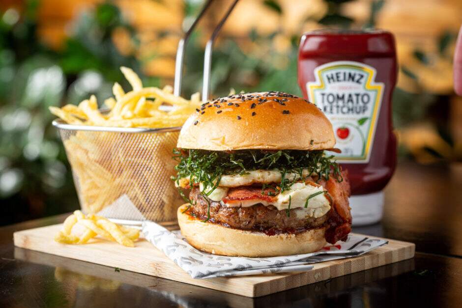 Pão artesanal com gergelim, burger de pernil, bacon crocante, ovo, cebola caramelizada com barbecue de bacon picante, sour cream e crispy de couve. Acompanha batata.